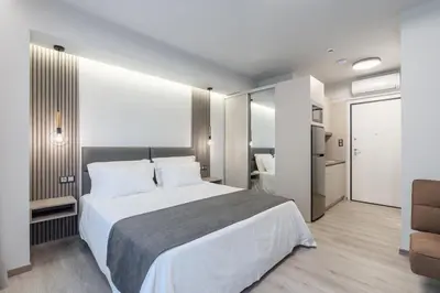 a bedroom with a large white bed and a chair at EN Suites Stylish & Comfort Stay near Acropolis in Athens