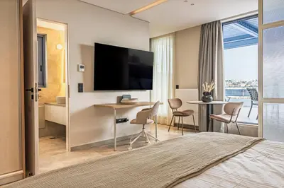 a hotel room with a television and a desk and chairs at Phaedrus Living Athens Luxury Residences Sunstone in Athens
