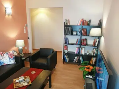 a living room with a couch and a book shelf at Acropolis Luxe Apartment in Athens