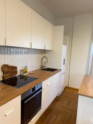 a kitchen with white cabinets and a black dishwasher at The Gardenian - 15 min from Athens Airport in Paianía