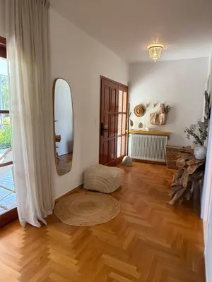 a living room with a wooden floor and a mirror at The Gardenian - 15 min from Athens Airport in Paianía