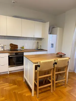 a kitchen with a wooden table and white cabinets at The Gardenian - 15 min from Athens Airport in Paianía