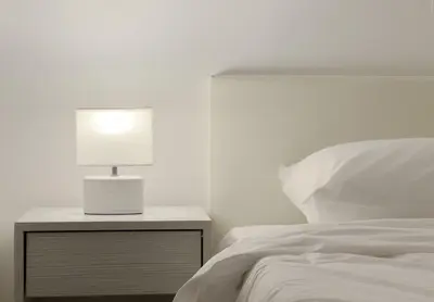 a bed with a nightstand with a lamp on it at Terpsixoris cozy apartment in Paleo Faliro in Athens