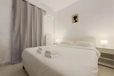a white bedroom with two white towels on a bed at Terpsixoris cozy apartment in Paleo Faliro in Athens