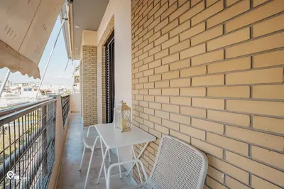 a table and chairs on a balcony with a brick wall at Golden Angel - Elegant Apartment in Egaleo-Athens in Athens
