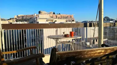 a wooden bench sitting on a balcony with a table at Aegli of Acropolis - 50mbps wifi in Athens