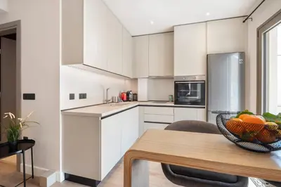 a kitchen with white cabinets and a bowl of fruit on a table at Lykavittos hill- penthouse in Athens
