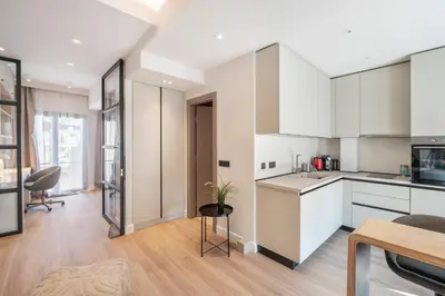 a kitchen and living room with white cabinets and a table at Lykavittos hill- penthouse in Athens