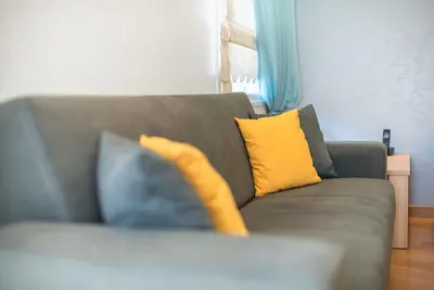 a couch with yellow and blue pillows on it at Agios Ioannis Metro station - Comfy Apartment in Athens