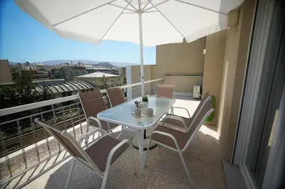 a table and chairs on a balcony with an umbrella at Athens city apartment B 100Mbps wifi in Athens