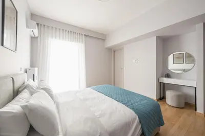 a white bedroom with a large bed and a mirror at Luxury Athens Living 3BR with Balcony in Athens