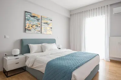 a white and blue bedroom with a bed and a window at Luxury Athens Living 3BR with Balcony in Athens