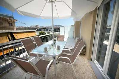 a white table and chairs on a balcony with an umbrella at Athens city 2 bedrooms apartment A 100Mbps wifi in Athens