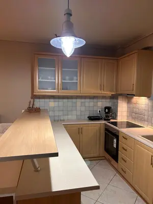 a kitchen with wooden cabinets and a light fixture at Glyfada sunset Apartment in Athens