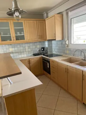 a kitchen with wooden cabinets and a sink at Glyfada sunset Apartment in Athens