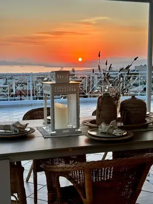a table with a candle on a balcony with the sunset at Glyfada sunset Apartment in Athens