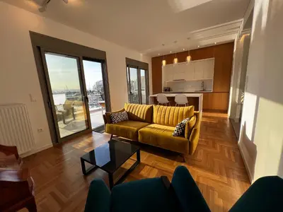 a living room with a yellow couch and a kitchen at Stunning View Zeas Marina - 2 bedrooms in Piraeus