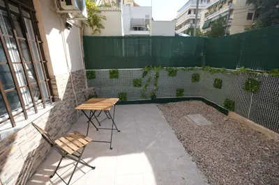 a patio with two chairs and a table and a fence at Lovely Front Garden 2 BDRM Nea Smyrni in Athens