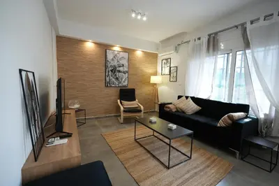 a living room with a black couch and a table at Lovely Front Garden 2 BDRM Nea Smyrni in Athens