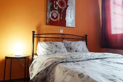 a bed in a bedroom with an orange wall at Near by Acropolis in Athens