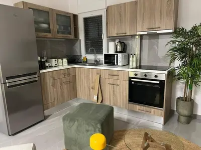 a kitchen with wooden cabinets and a stainless steel refrigerator at Vibrant 2BR in Koukaki in Athens