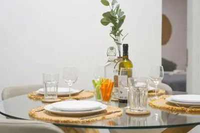 a glass table with plates and glasses and a bottle of wine at Vibrant 2BR in Koukaki in Athens
