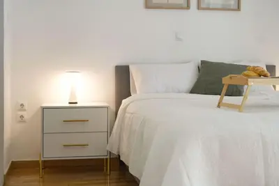 a bedroom with a white bed and a nightstand with a lamp at Vibrant 2BR in Koukaki in Athens