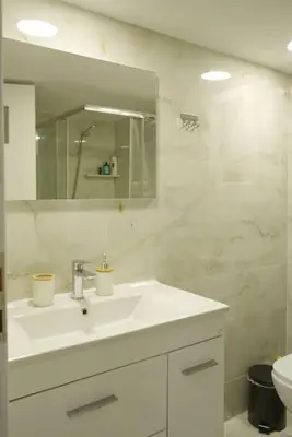a white bathroom with a sink and a mirror at Vibrant 2BR in Koukaki in Athens