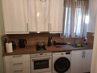 a kitchen with white cabinets and a washing machine at Homy in Athens
