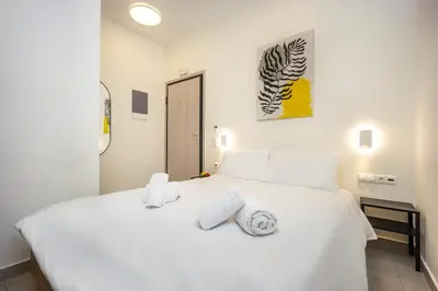 a white bedroom with a white bed with towels on it at DownTown Vibes 2 in Athens