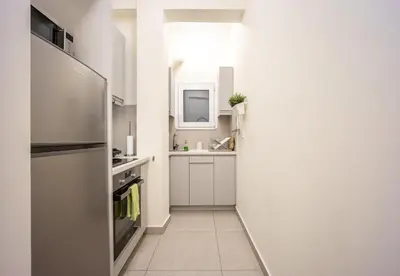 a white kitchen with a refrigerator and a sink at DownTown vibes #1 in Athens