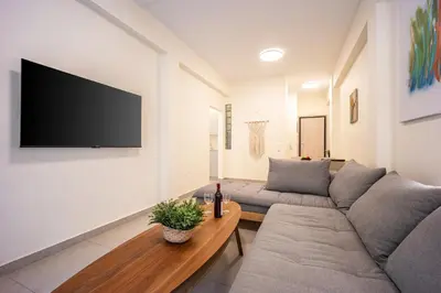 a living room with a couch and a tv on a wall at DownTown vibes #1 in Athens
