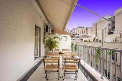 a balcony with wooden tables and chairs on a building at DownTown vibes #1 in Athens