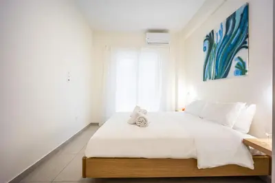a bedroom with a large white bed with a blue painting at DownTown vibes #1 in Athens