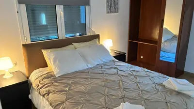 a bedroom with a bed with two night stands and two windows at VK apartment in Athens