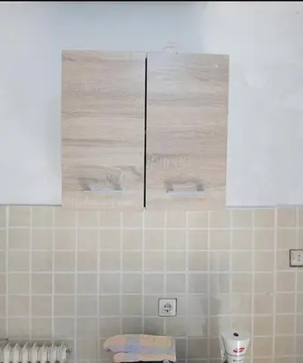 a bathroom with a tiled wall with a picture above a toilet at Simple apartment in Athens