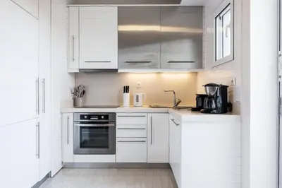 a white kitchen with white cabinets and appliances at Elegant & Roomy 3-Bedroom Apartment in the Heart of Glyfada in Athens