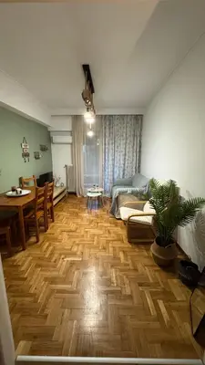 a living room with a wooden floor and a dining room at Olēa House at Monastiraki in Athens