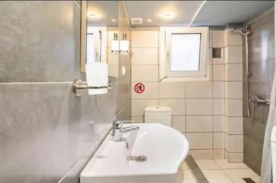 a bathroom with a sink and a toilet and a window at Έξυπνο στουντιο ημιυπόγειο στην Αθήνα με αυλή in Athens