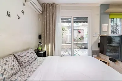 a bedroom with a white bed and a television at Έξυπνο στουντιο ημιυπόγειο στην Αθήνα με αυλή in Athens