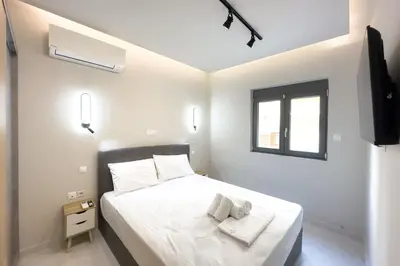 a white bedroom with a bed and a window at Villa Redi Relaxing Spa in Piraeus