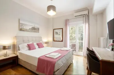 a bedroom with a large bed with pink pillows at Koukaki Hideaway Suite in Athens
