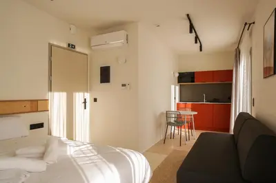 a bedroom with a bed and a kitchen with a table at Mooeve Psyri in Athens