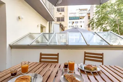 a wooden table with two plates of food and orange juice at Mooeve Psyri in Athens