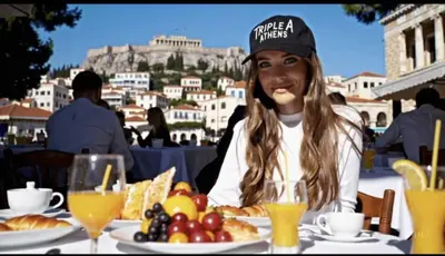 a woman sitting at a table with a plate of food at Triple A - Psiri Fruit Market Artistic Studios - FREE Parking in Athens