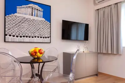 a dining room with a table and chairs and a tv at Synathens Syntagma Apartments in Athens