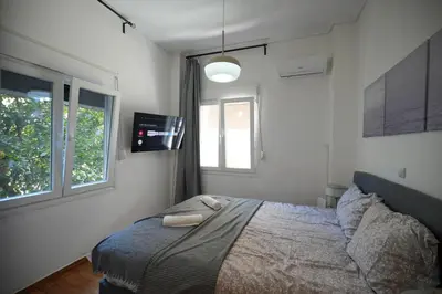 a bedroom with a bed and two windows at The Cozy Studio, Nea Smyrni in Athens