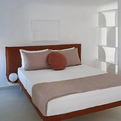 a bed with white sheets and a brown pillow on it at BlueNote Suites in Athens