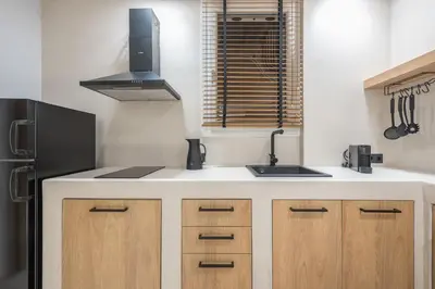 a kitchen with a black refrigerator and wooden cabinets at Exarcheia Luxury Apartment in Athens