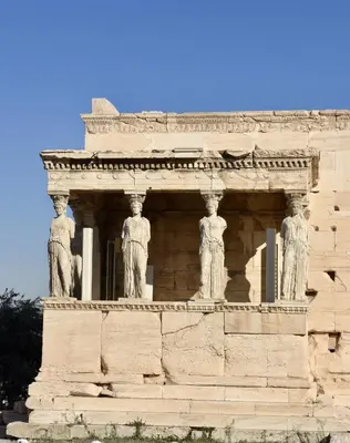 a stone building with three statues on it at The Acropolis Penthouse in Athens